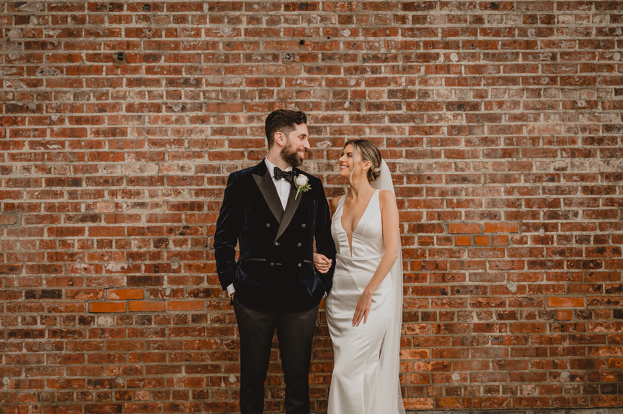 bride and groom hold hands standing in front of brick wall at Maritime Parc