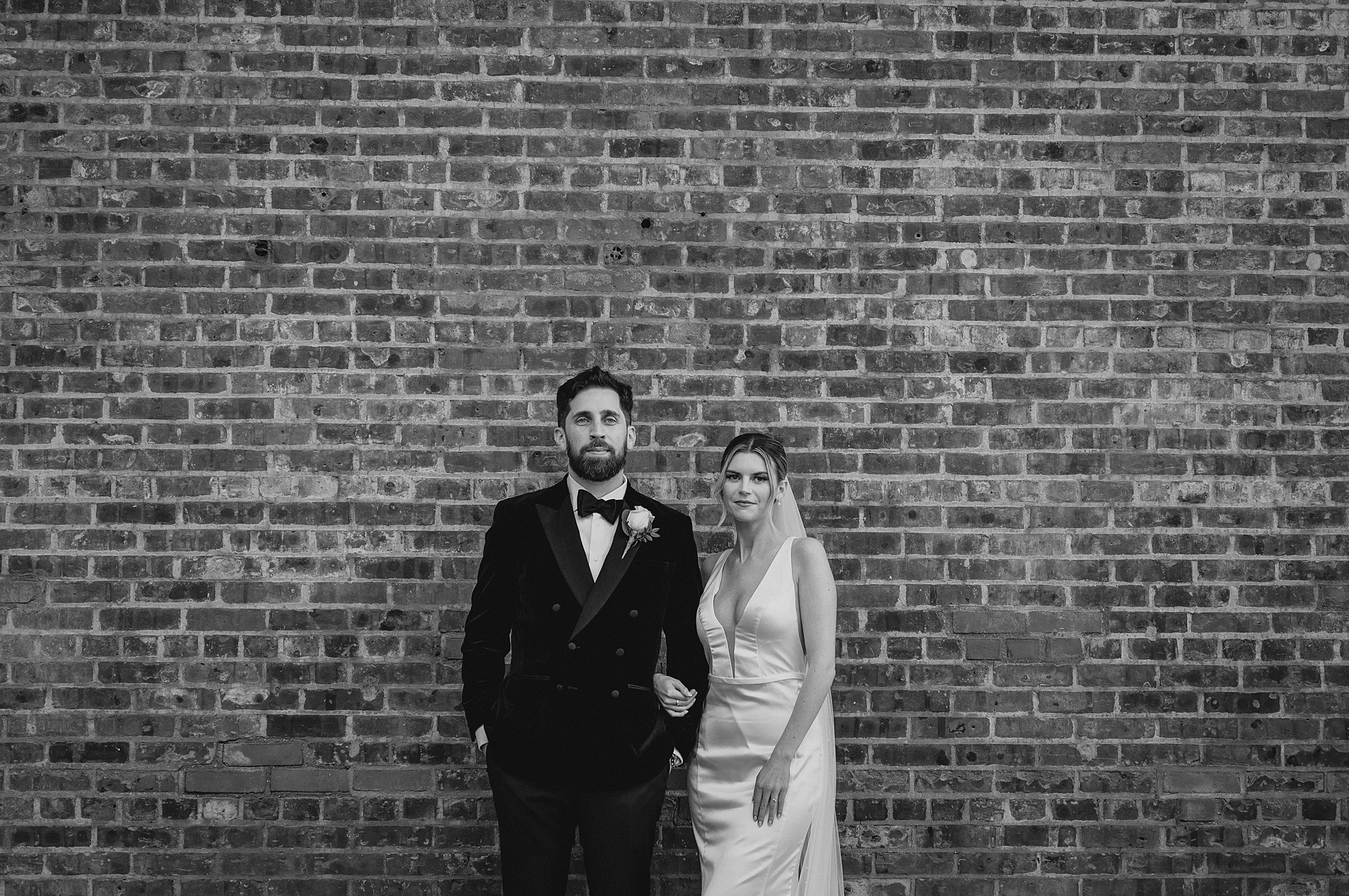 bride and groom hold hands standing in front of brick wall at Maritime Parc