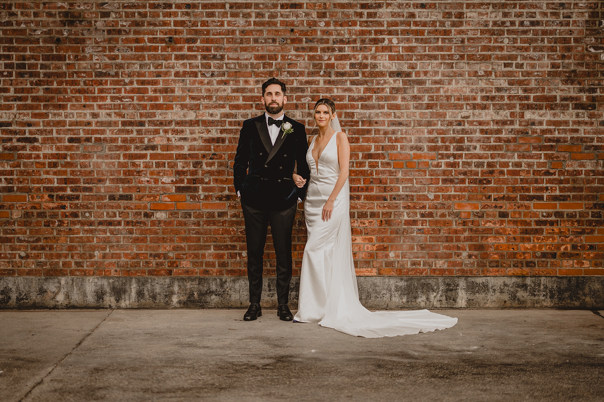 bride and groom hold hands standing in front of brick wall at Maritime Parc