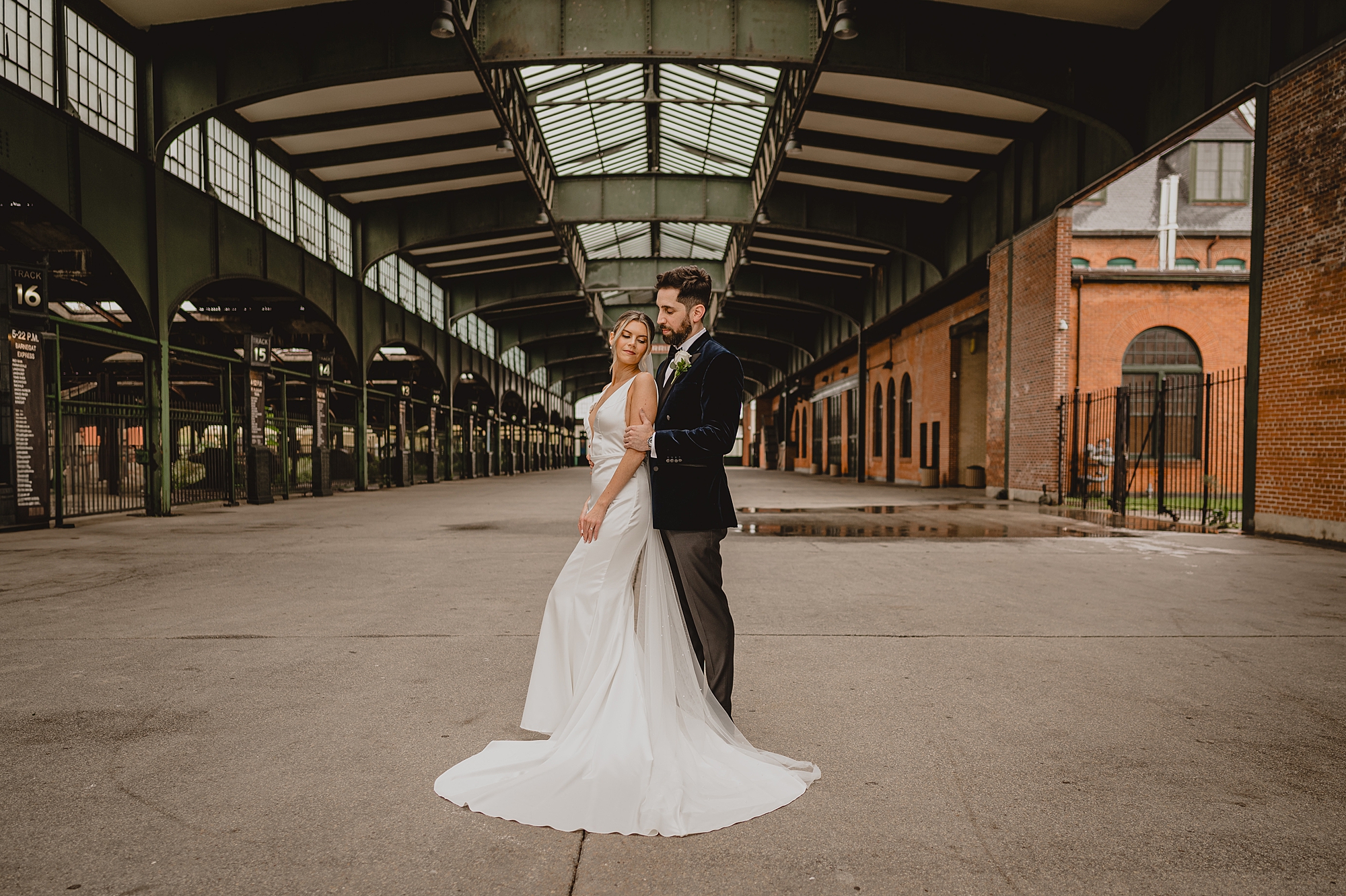 groom stands behind groom hugging inside Maritime Parc