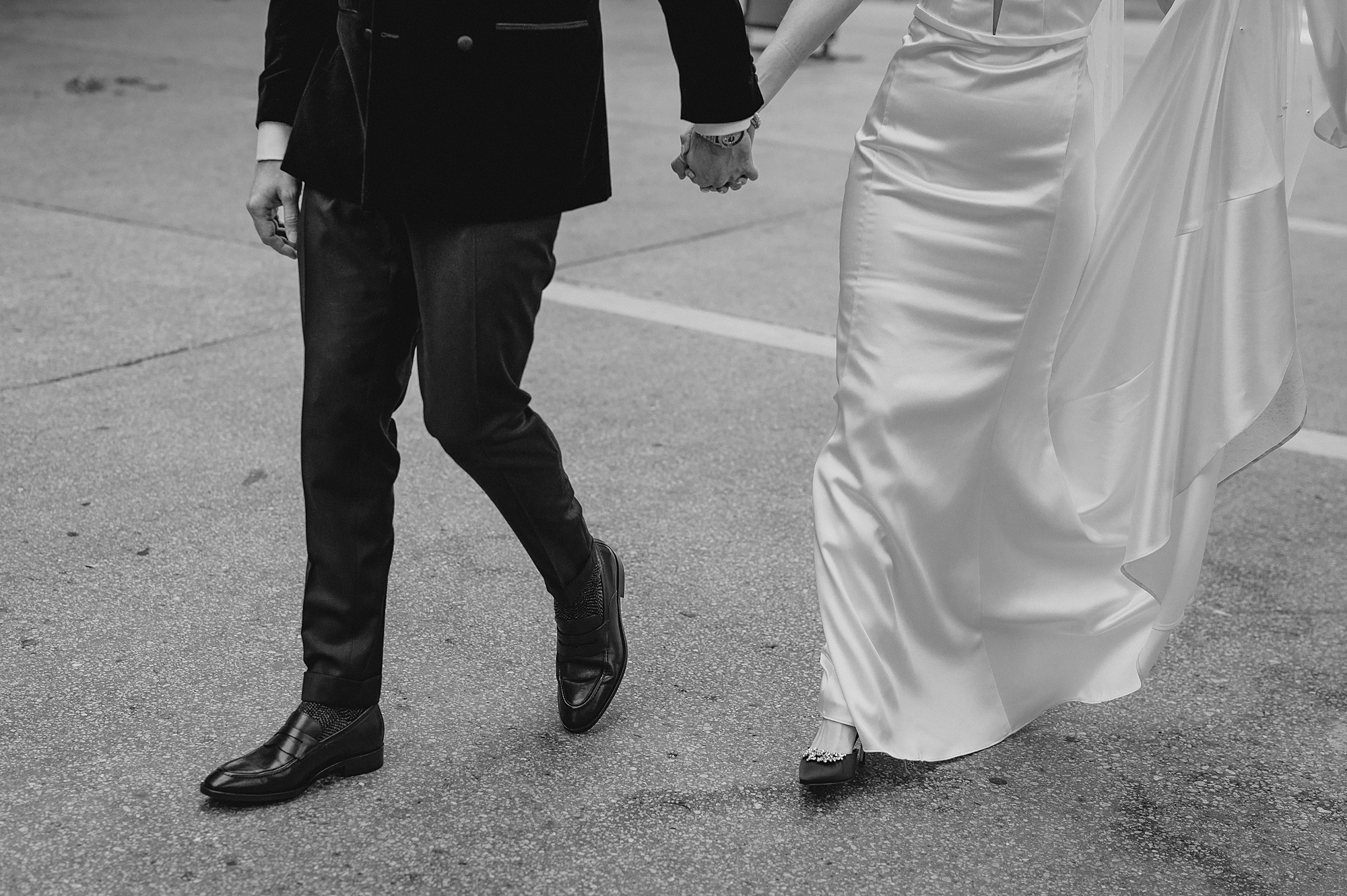 bride and groom hold hands walking across sidewalk in Jersey City