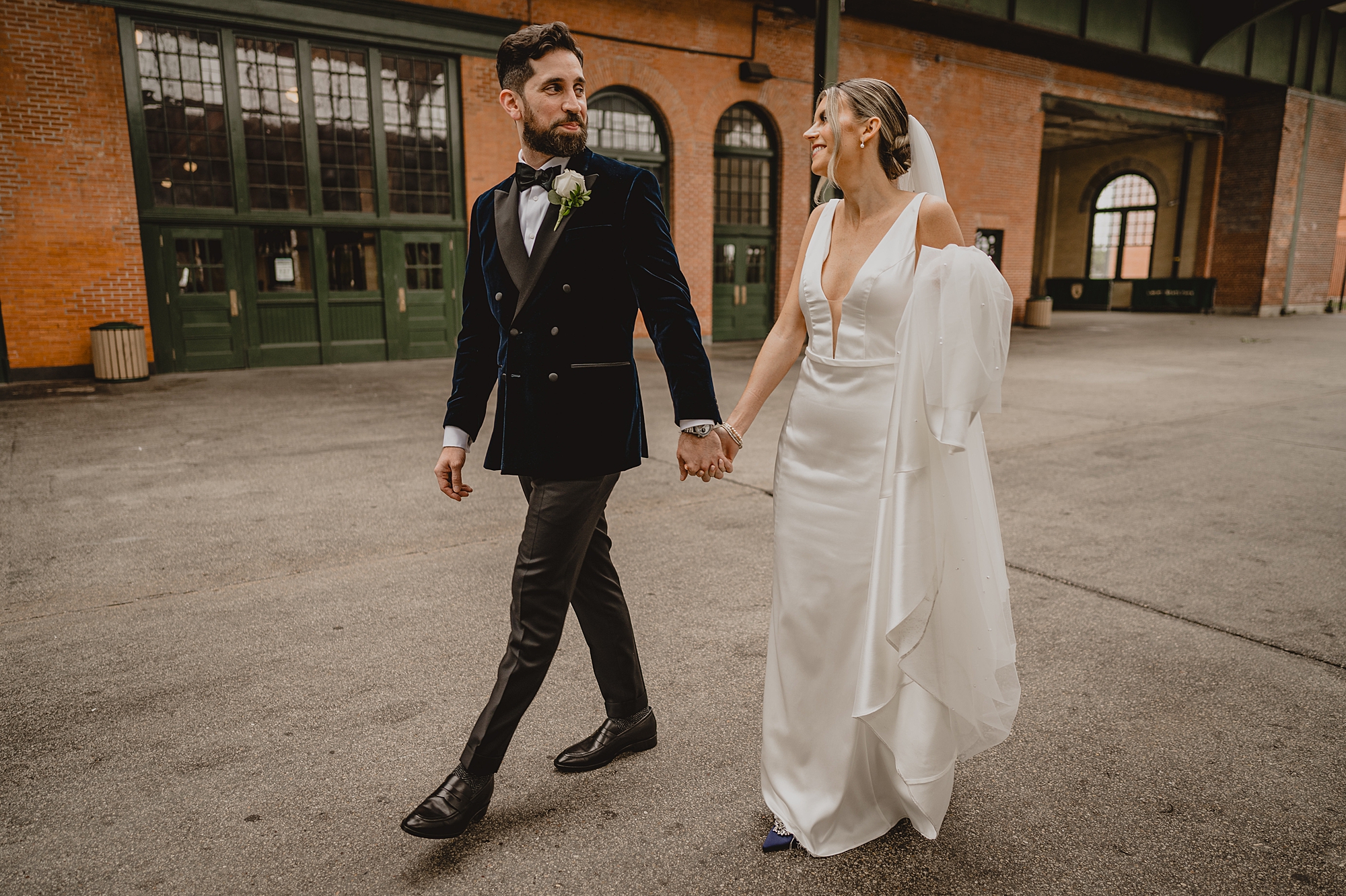 bride and groom hold hands walking through Jersey City outside Maritime Parc