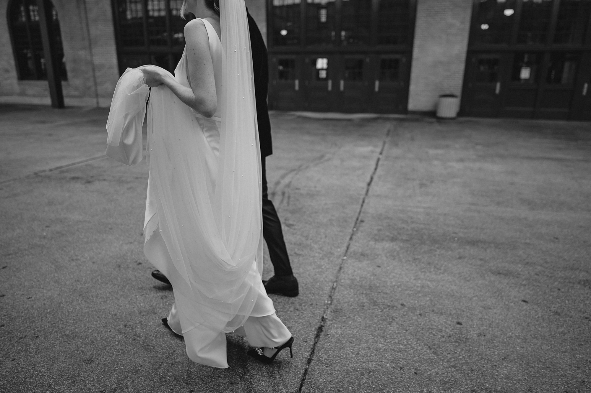 bride and groom hold hands walking outside Maritime Parc