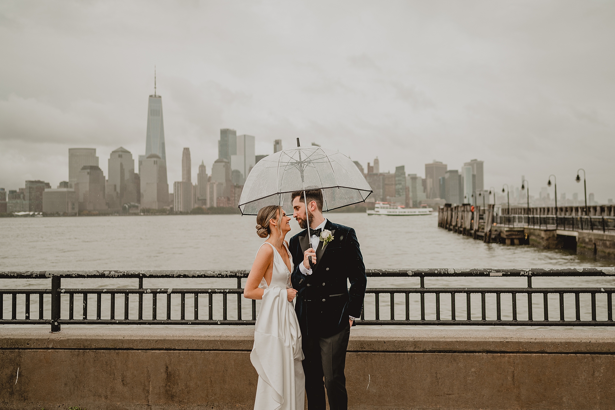 bride and groom hug under clear umbrella during rainy wedding at Maritime Parc