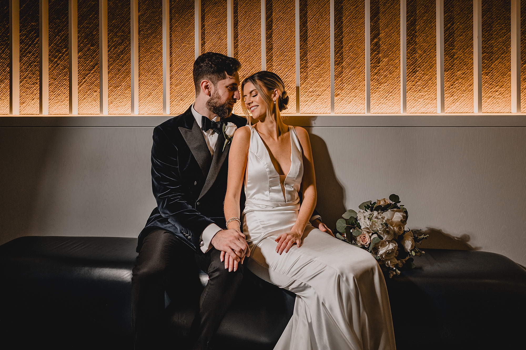bride and groom sit on bench inside Maritime Parc
