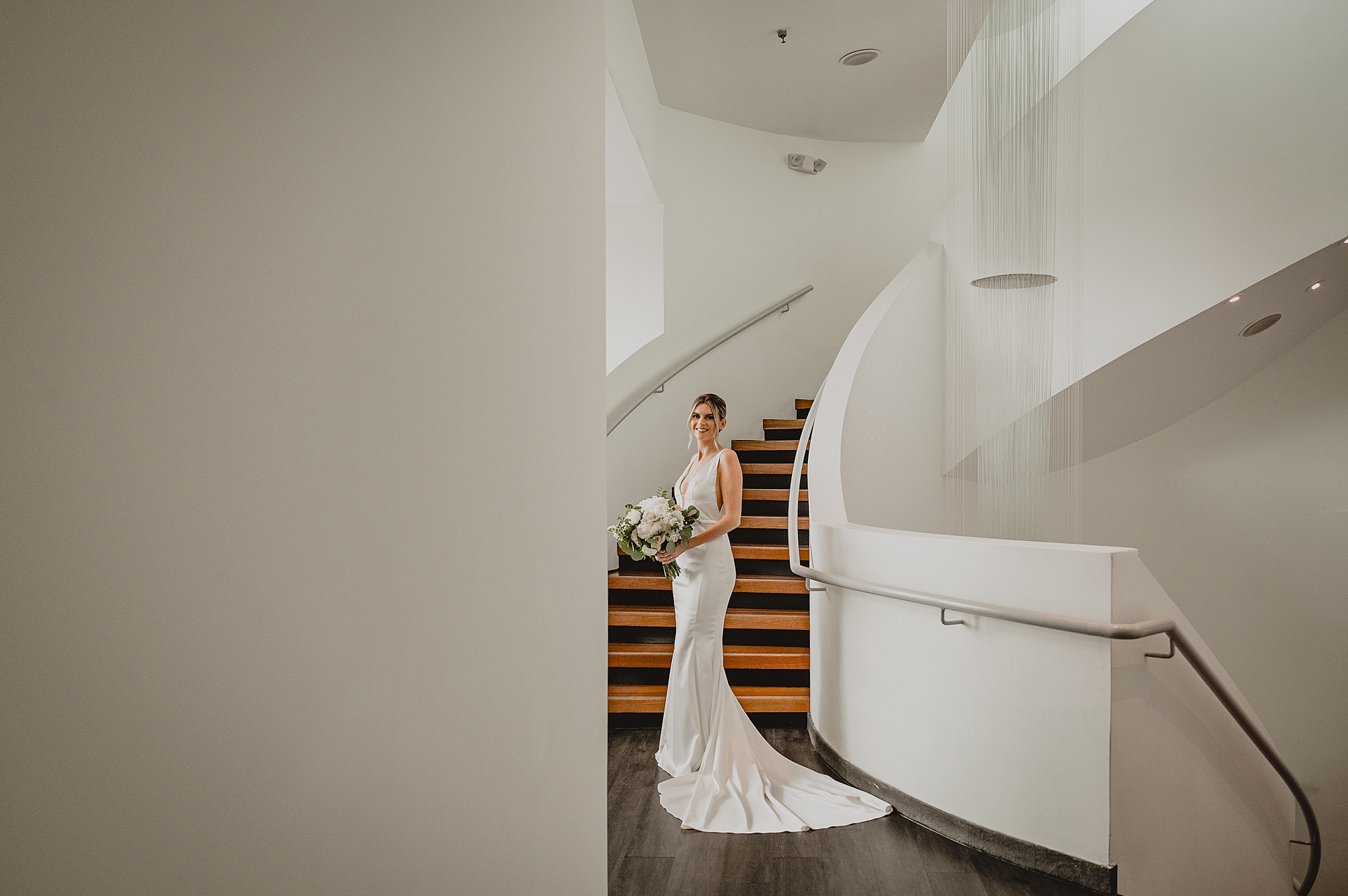 bride stands in front of white staircase inside Maritime Parc