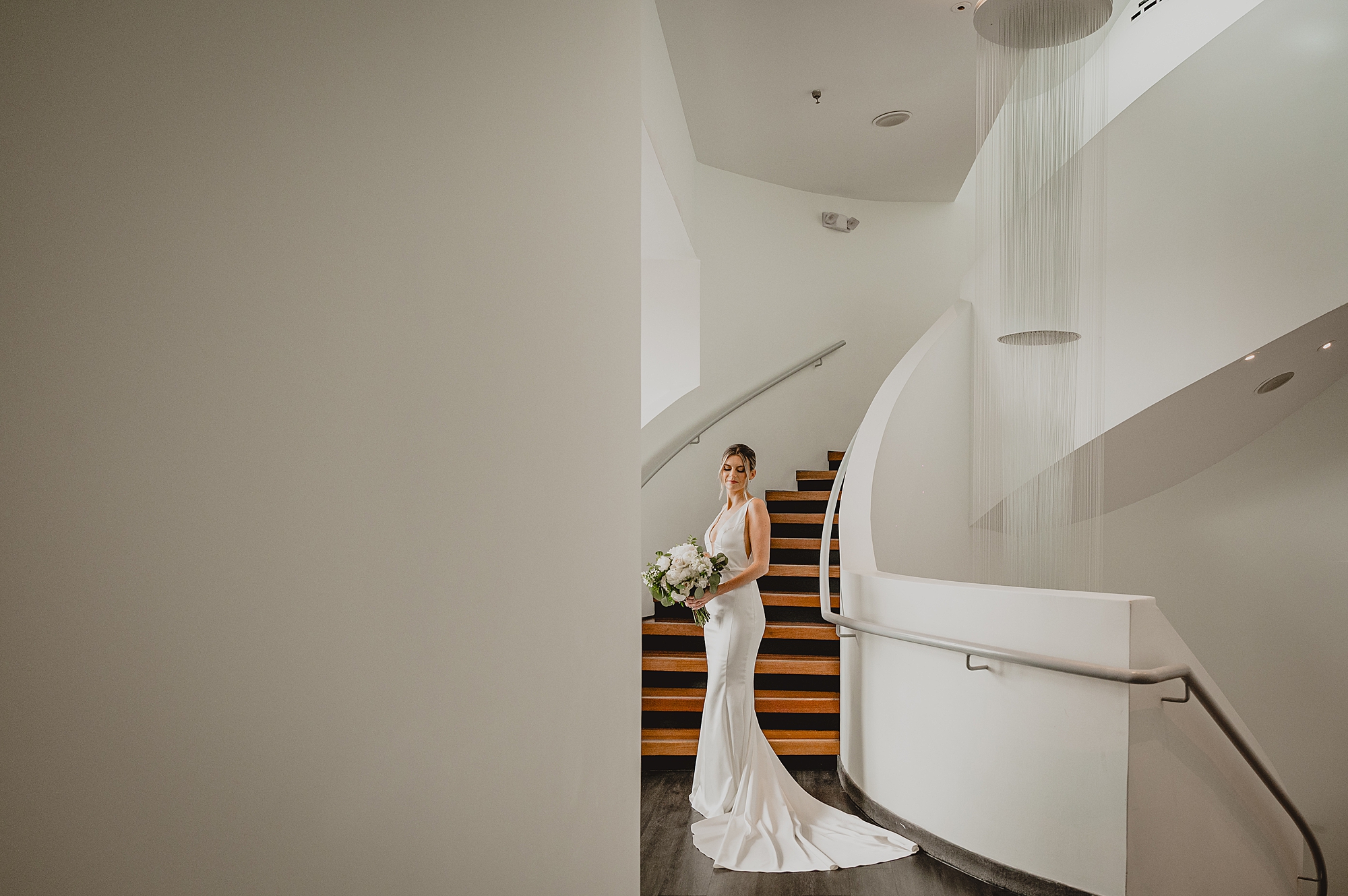 bride holds bouquet of white flowers inside Maritime Parc near staircase