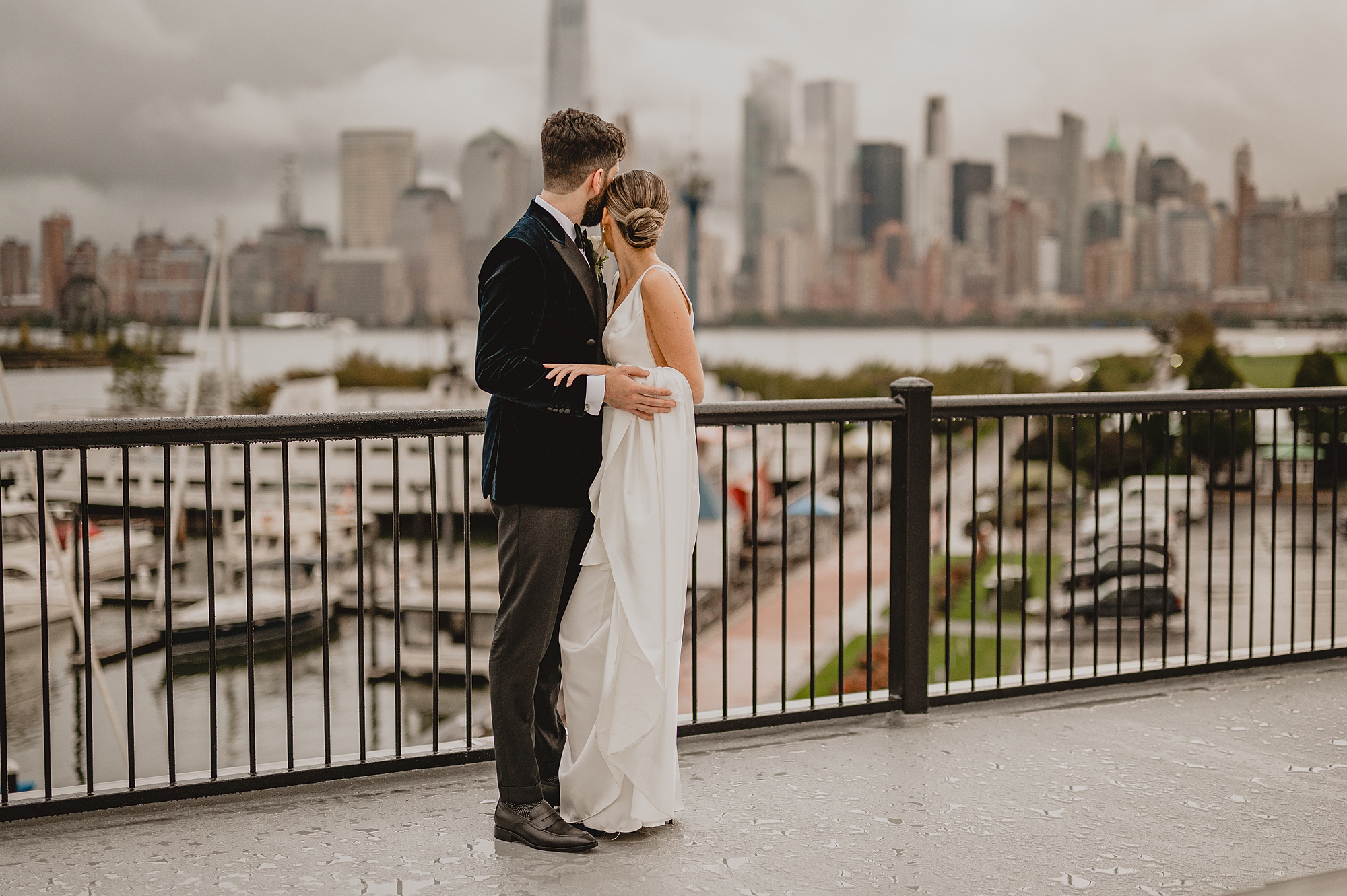 newlyweds hug on balcony overlooking NYC skyline