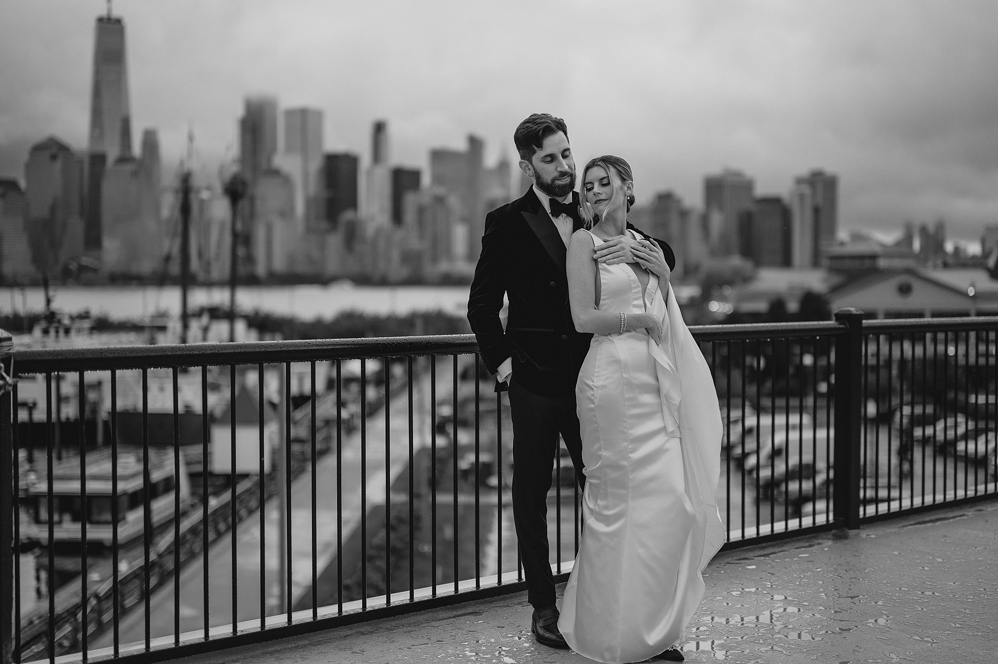 newlyweds hug on balcony overlooking NYC skyline