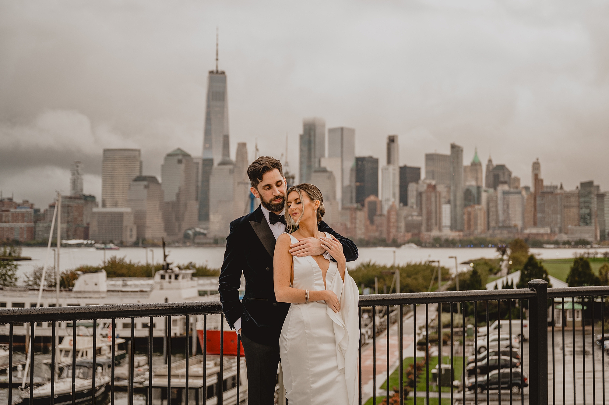 newlyweds hug on balcony overlooking NYC skyline