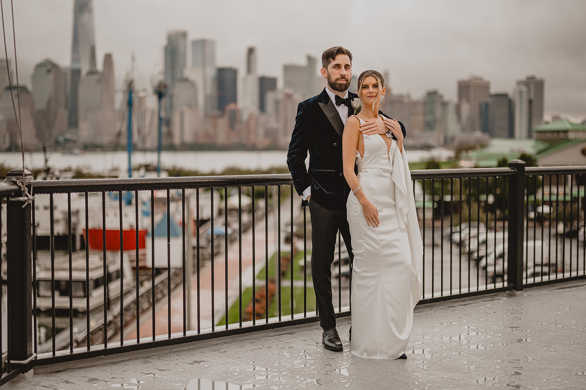 newlyweds hug on balcony overlooking NYC skyline