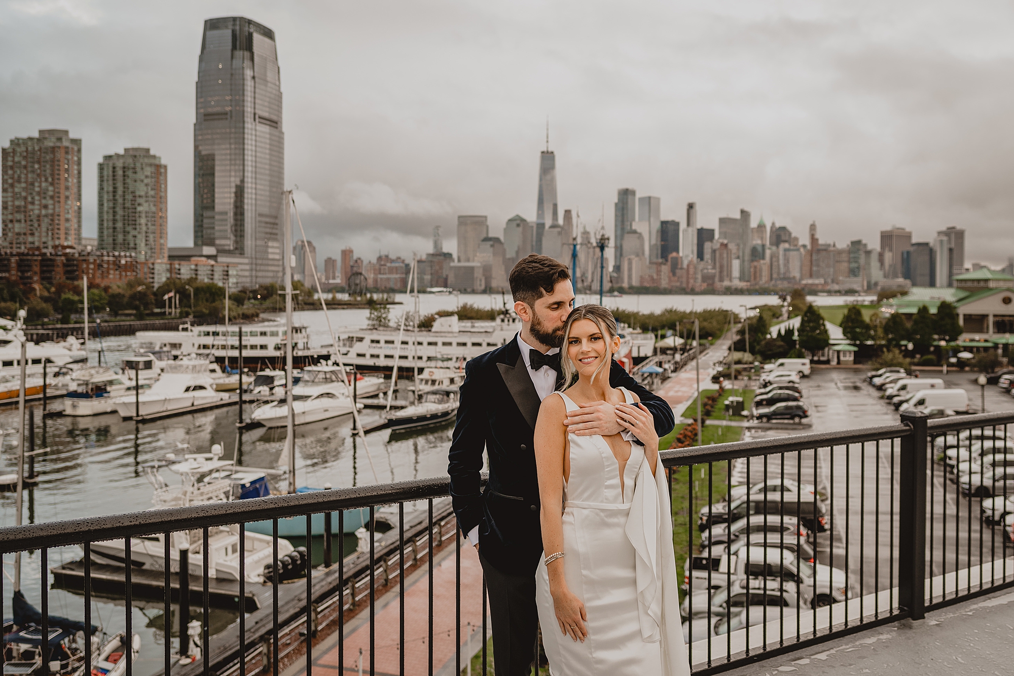 newlyweds hug on balcony overlooking NYC skyline