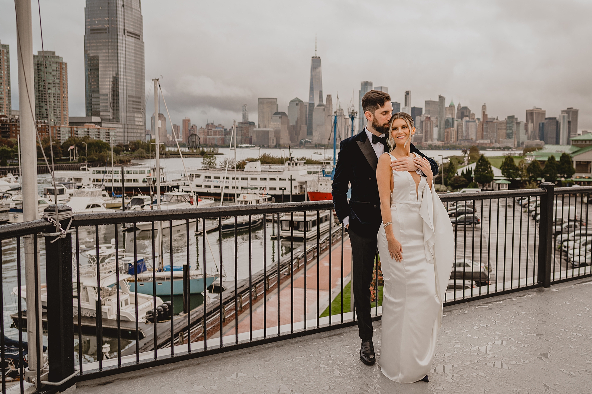 newlyweds hug on balcony overlooking NYC skyline