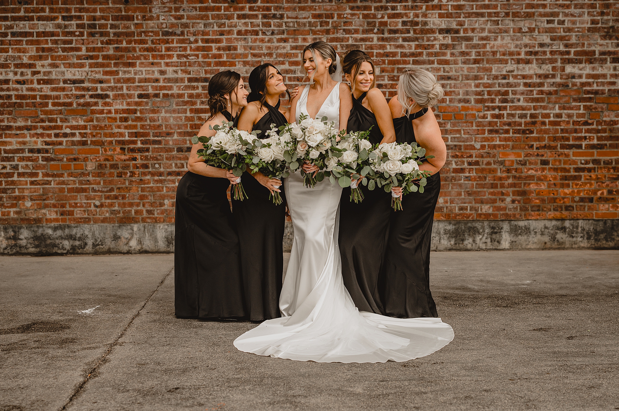 bride smiles with bridesmaids in black dresses for wedding at Maritime Parc
