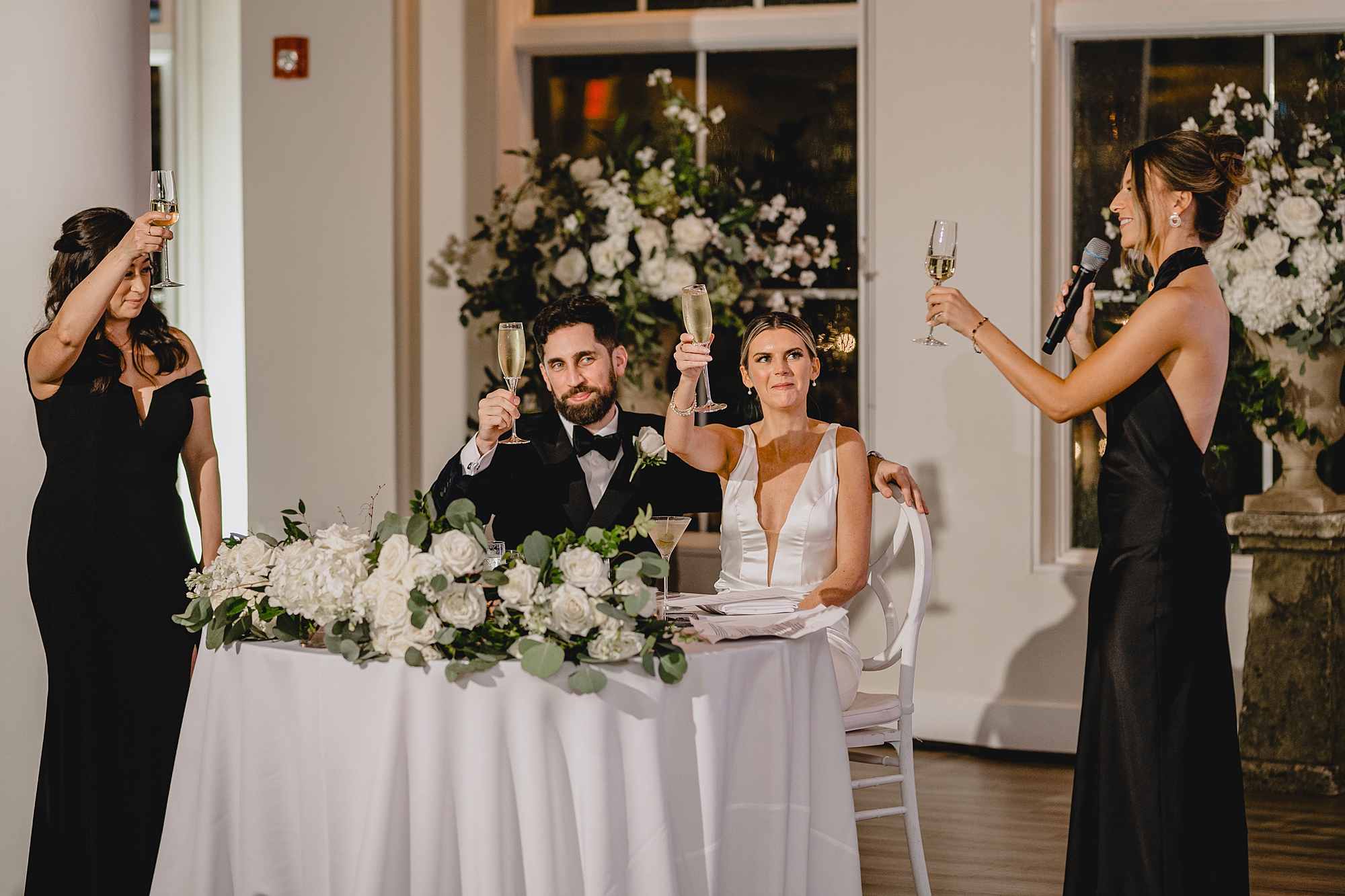 newlyweds toast with champagne at sweetheart table during NJ wedding reception