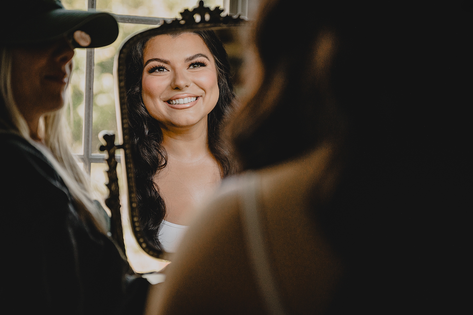 bride grins in mirror reflection during prep for wedding day at Crossed Keys Estate