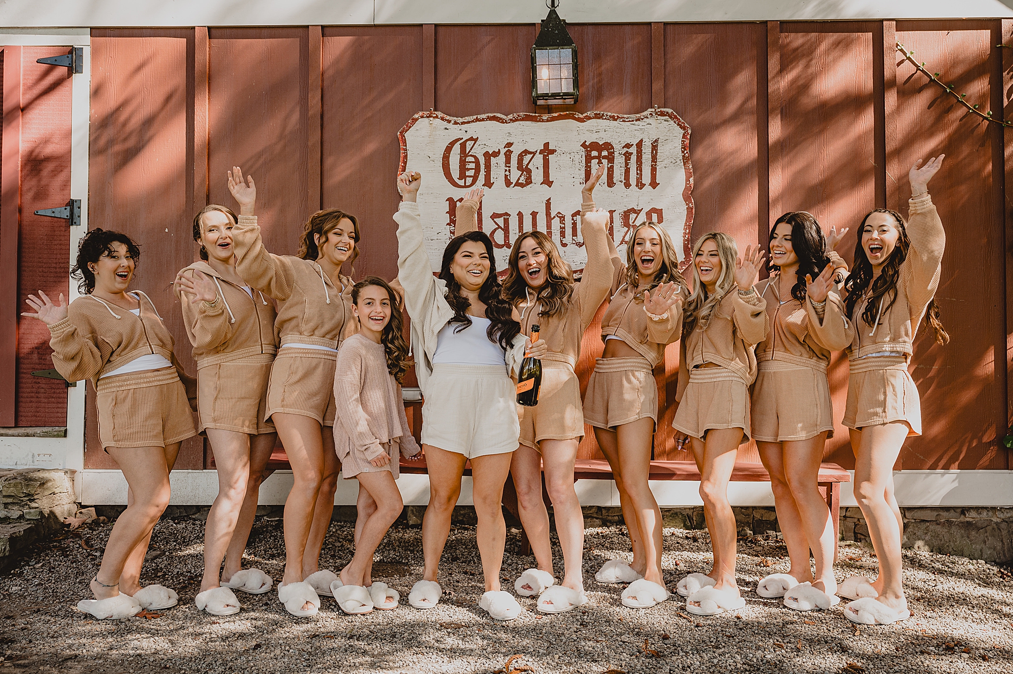 bride and bridesmaids hold champagne outside Grist Mill at Crossed Keys Estate