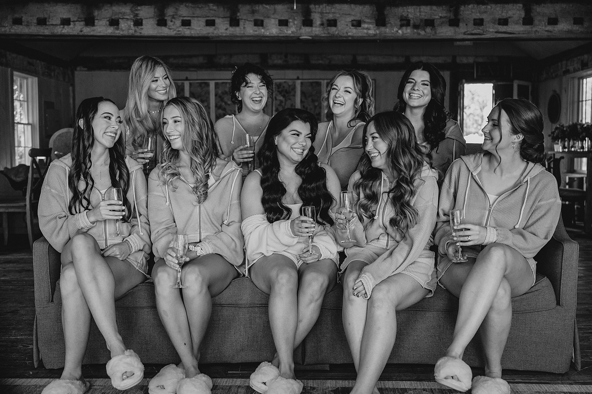 bride and bridesmaids sit on couch inside bridal suite at Crossed Keys Estate
