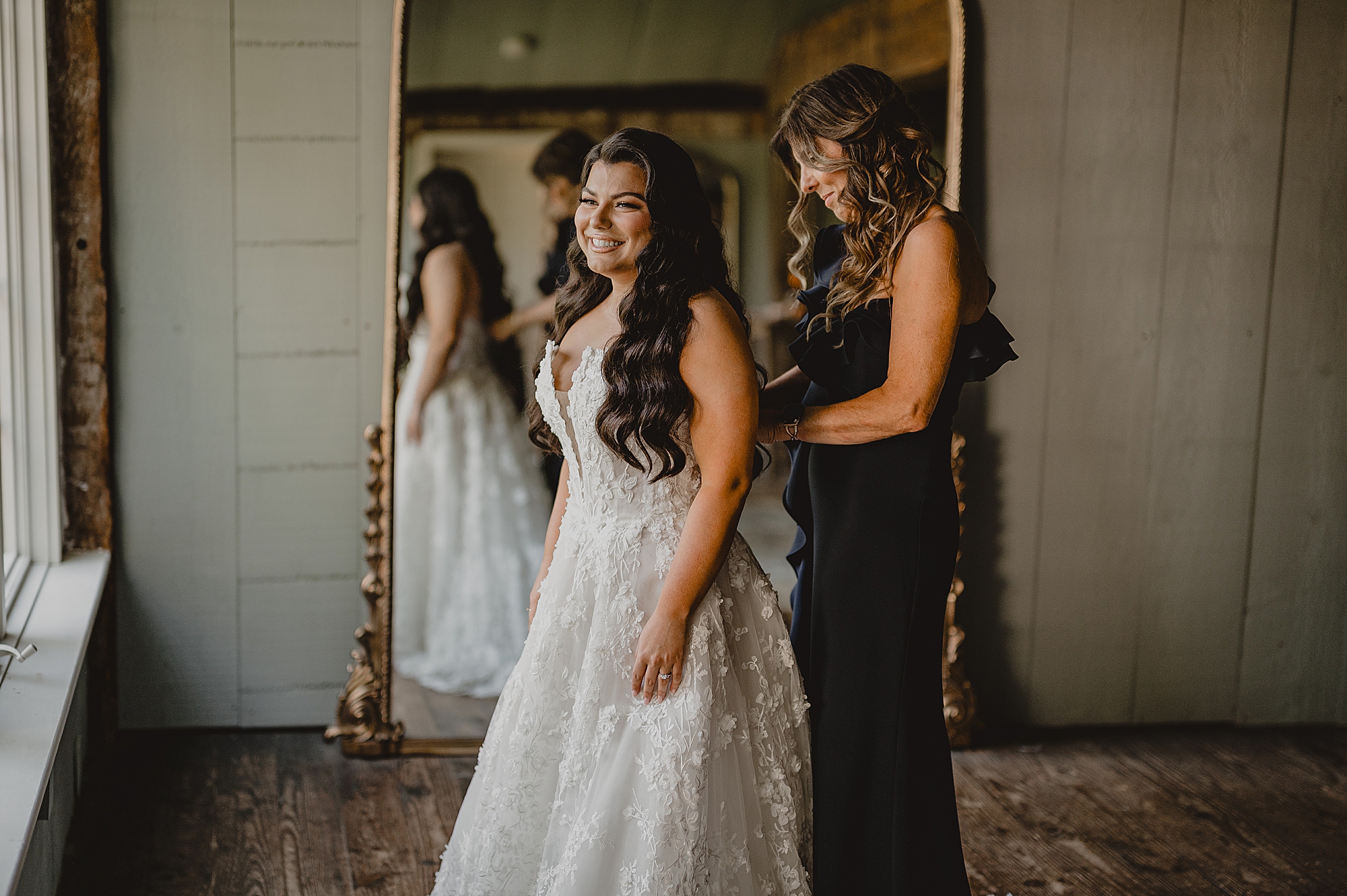 mother helps bride into wedding dress in suite at Crossed Keys Estate