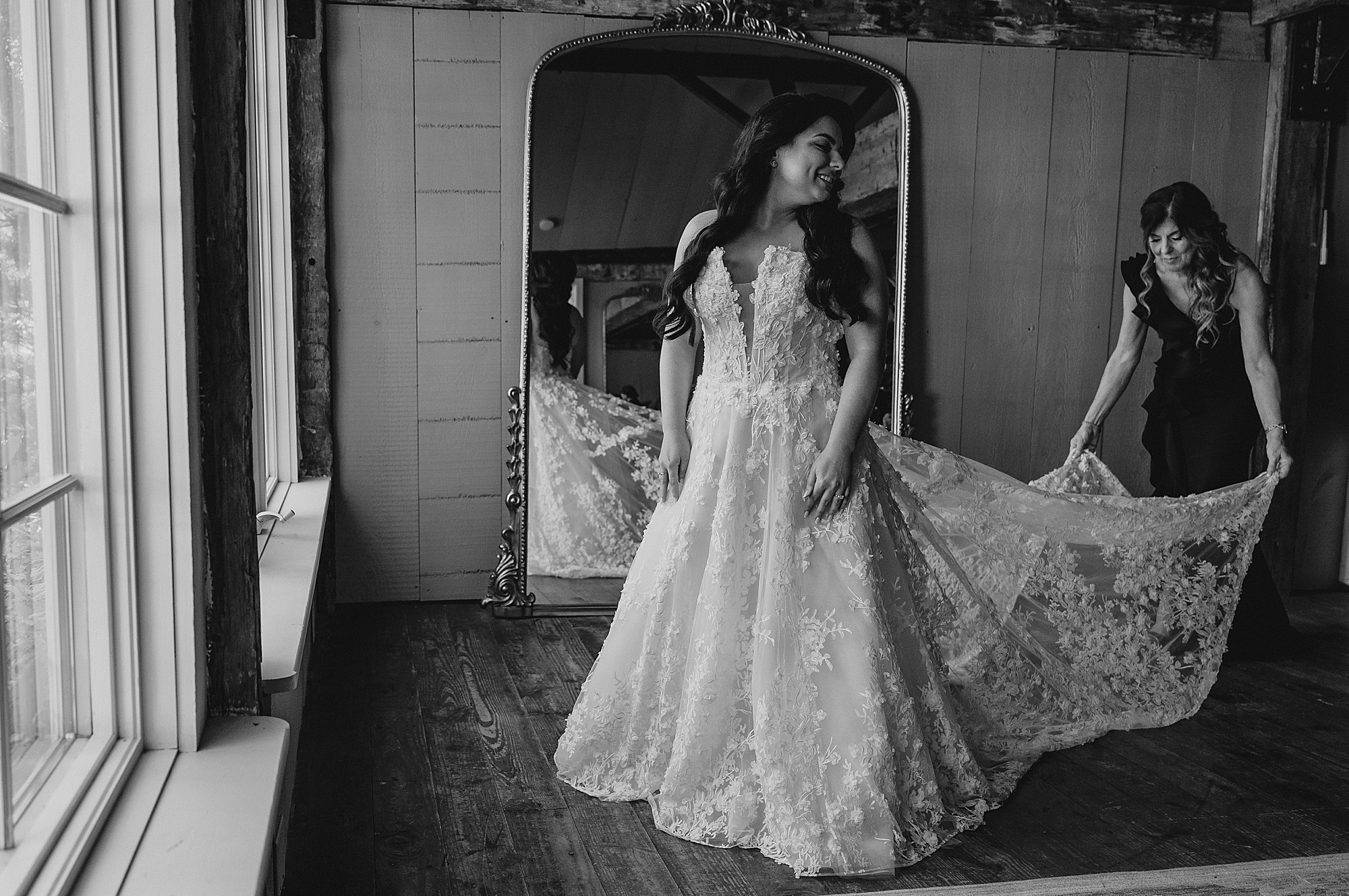 bridesmaid holds out skirt of wedding gown for bride