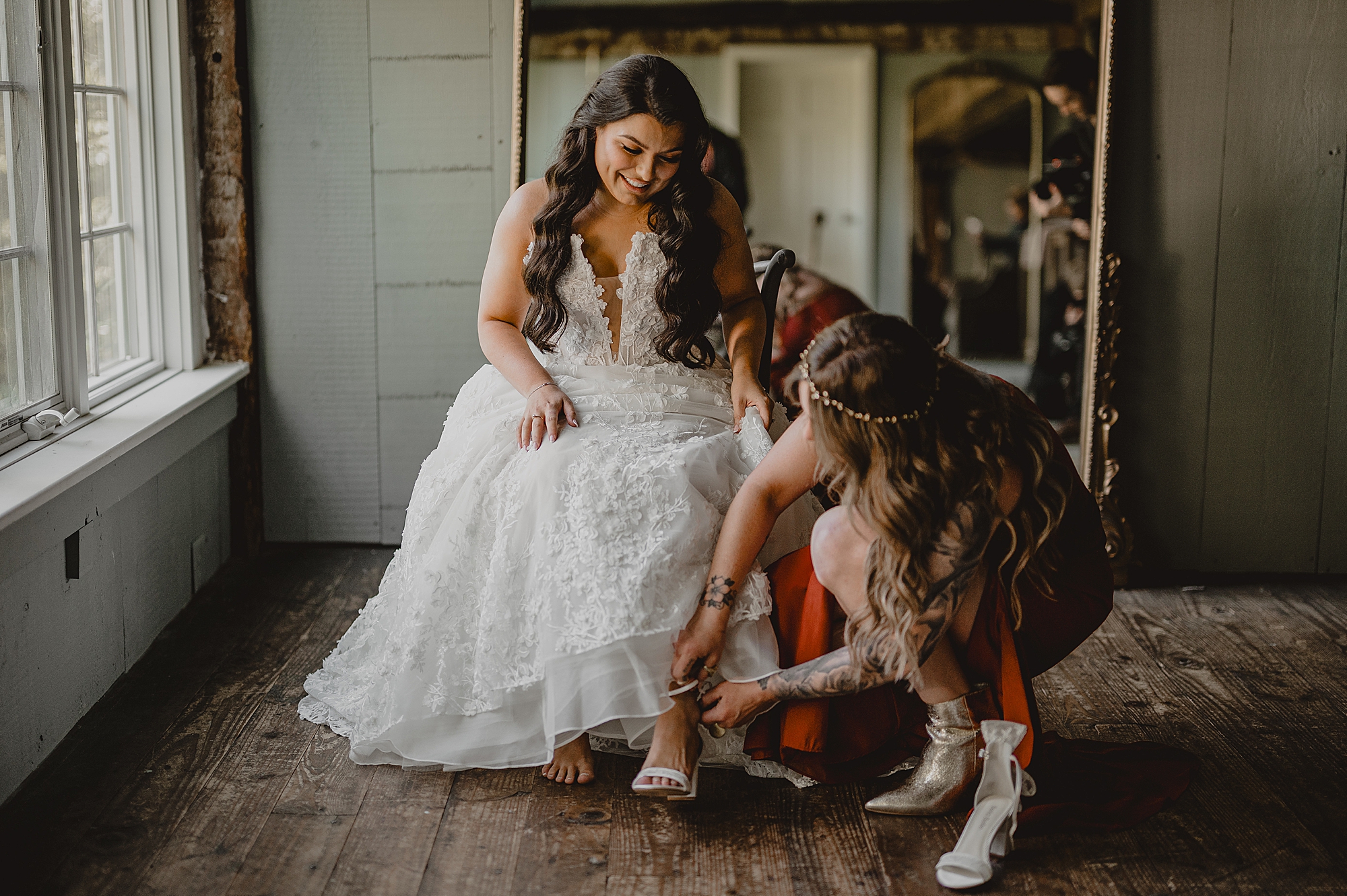 bridesmaid helps bride with shoes on morning of wedding at Crossed Keys Estate