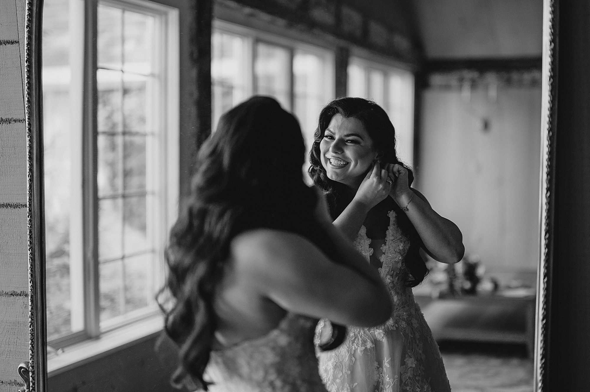 bride adjusts earrings in front of mirror at Crossed Keys Estate