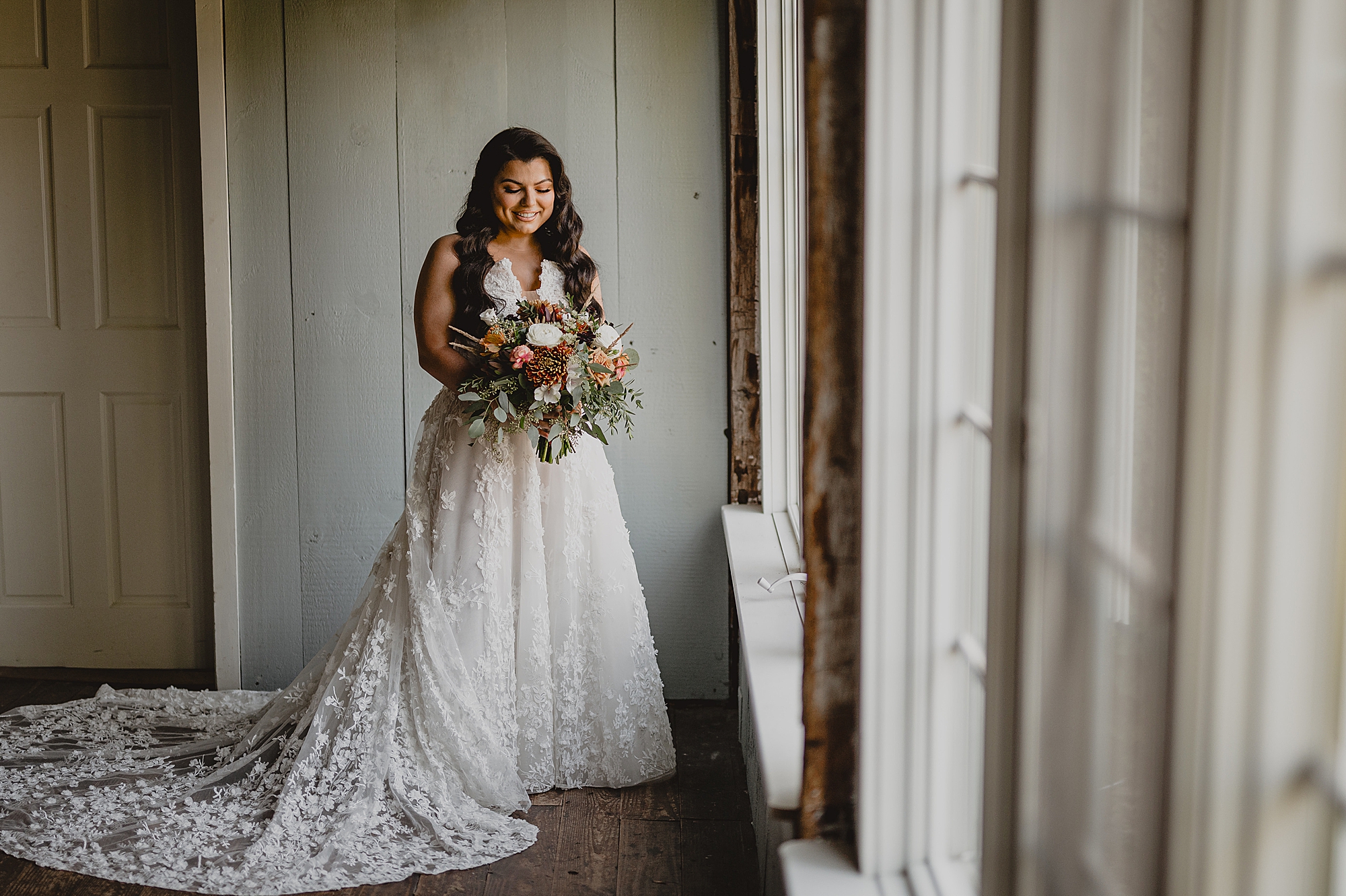 bride holds bouquet of fall flowers by window at Crossed Keys Estate