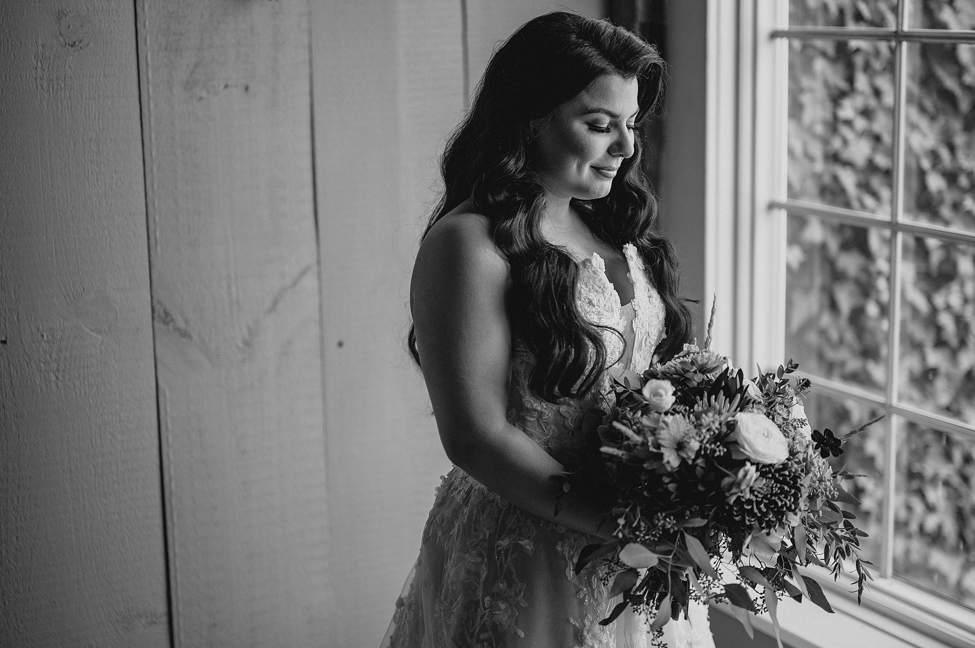 brunette bride looks down at bouquet of flowers on fall wedding day at Crossed Keys Estate