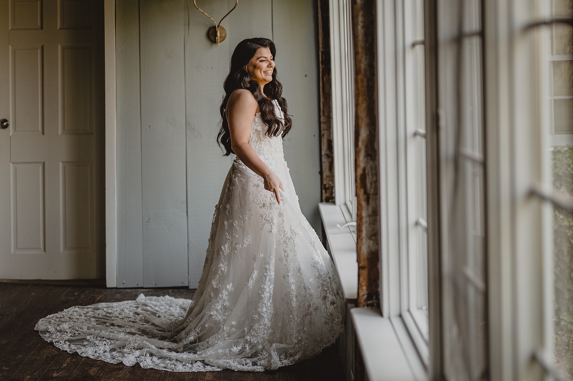 bride laughs standing in front of windows at Crossed Keys Estate
