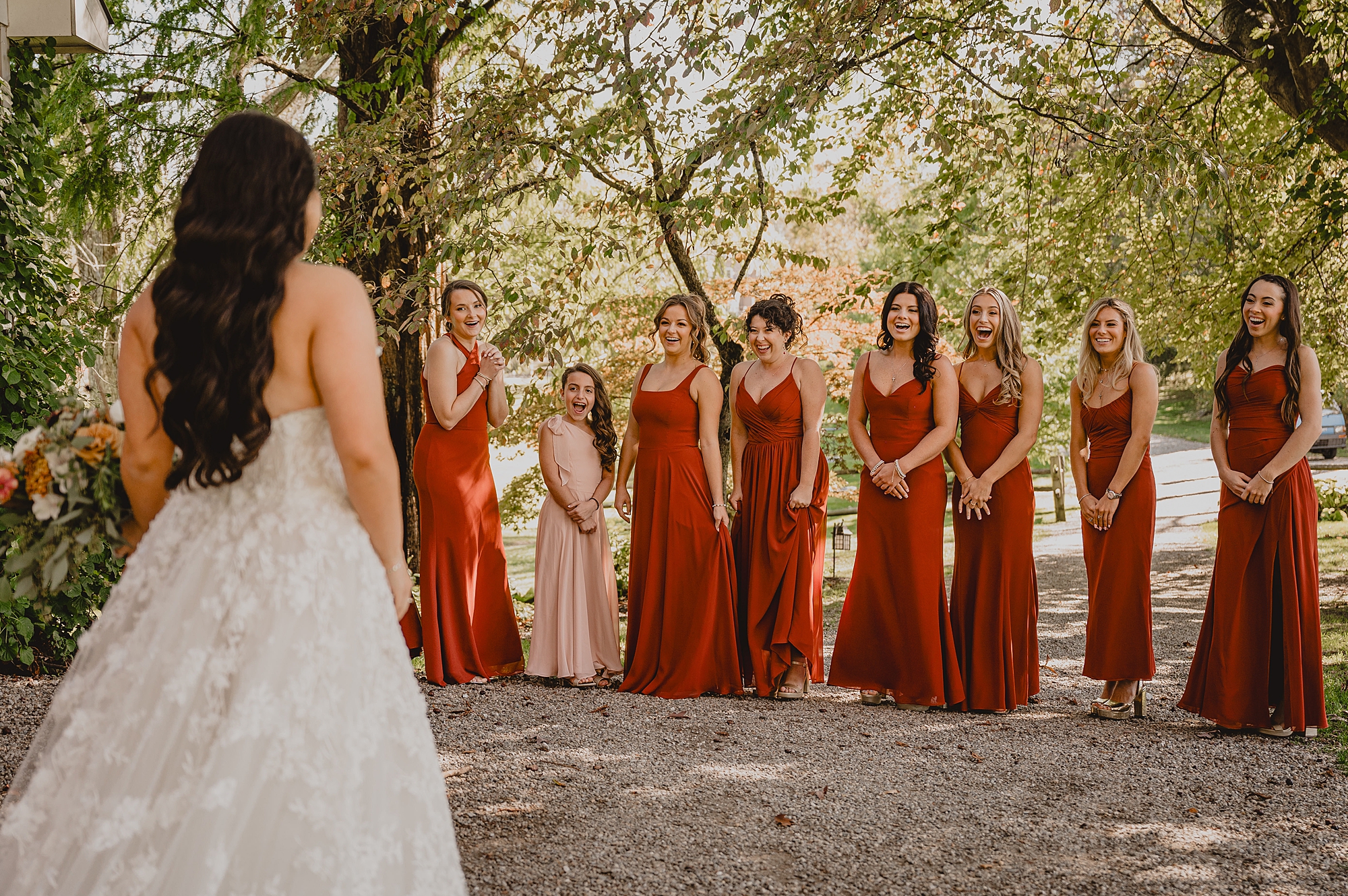 bride has first look with bridesmaids in burnt orange gowns
