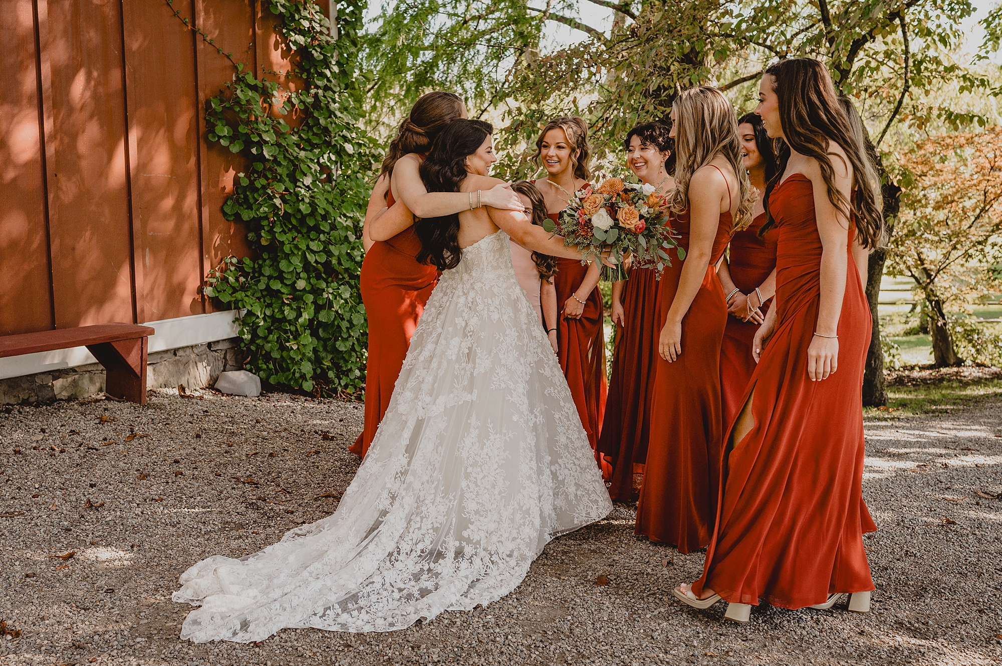 bride hugs bridesmaids after first look outside the Grist Mill
