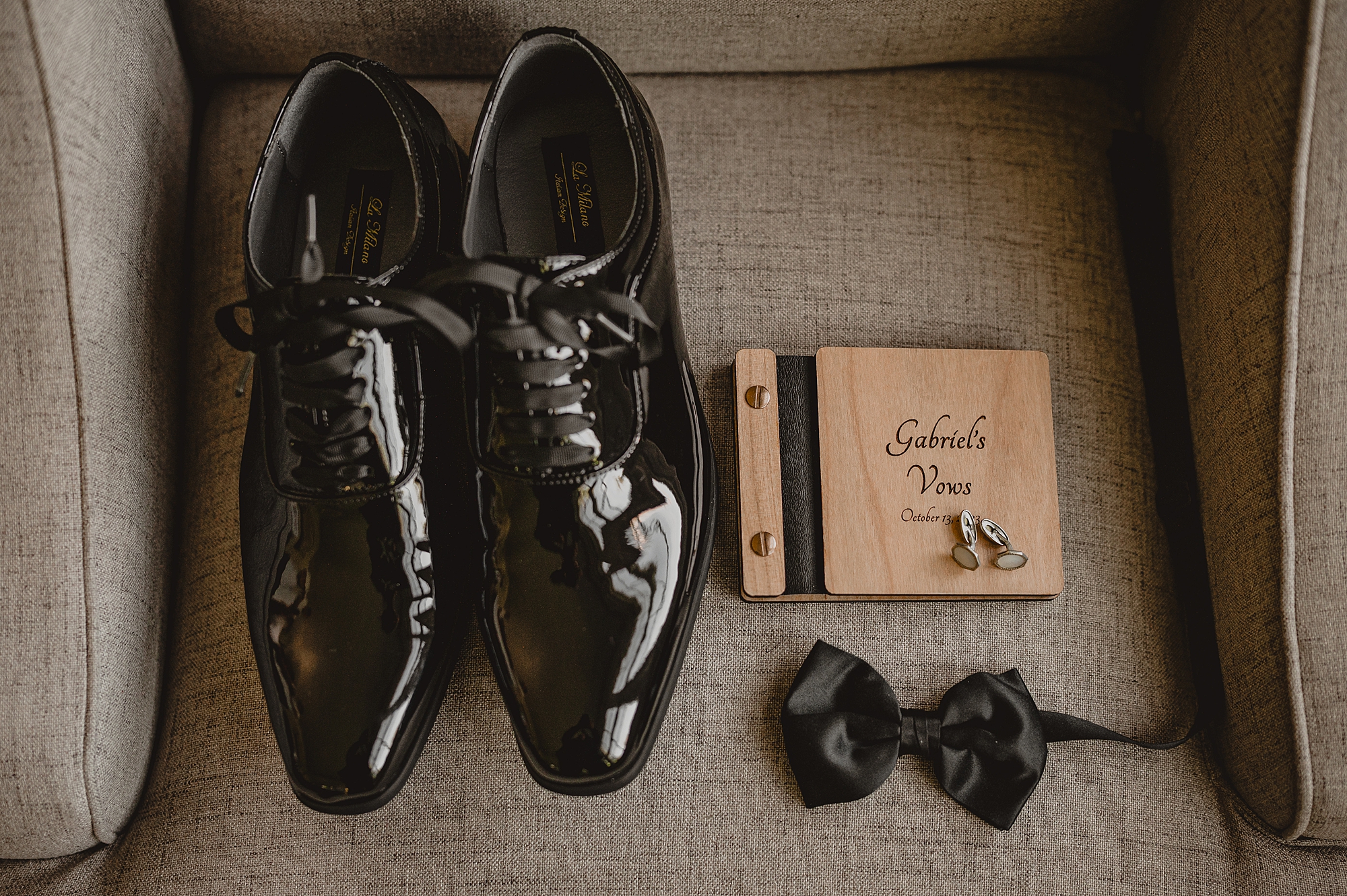 groom's black shoes, bowtie and vow booklet
