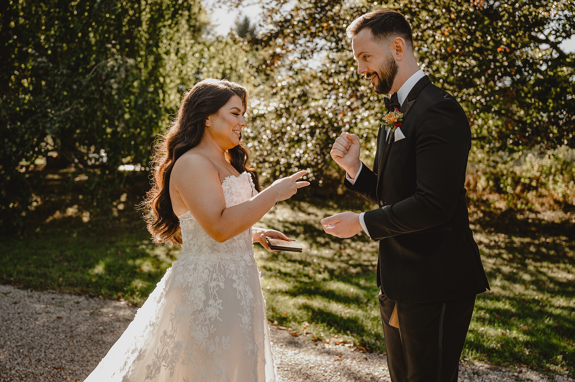 bride reaches for groom standing in gardens at Crossed Keys Estate