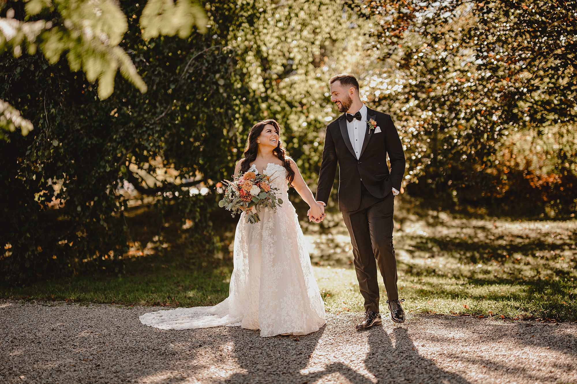 bride and groom hold hands walking through garden at Crossed Keys Estate