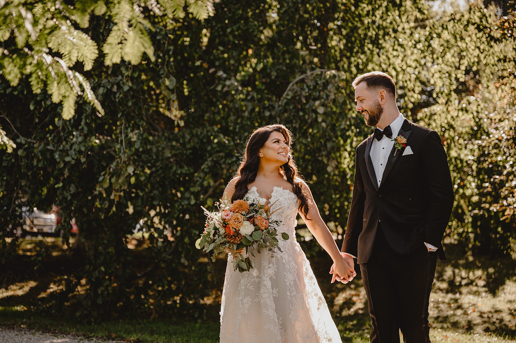 newlyweds hold hands walking through garden at Crossed Keys Estate