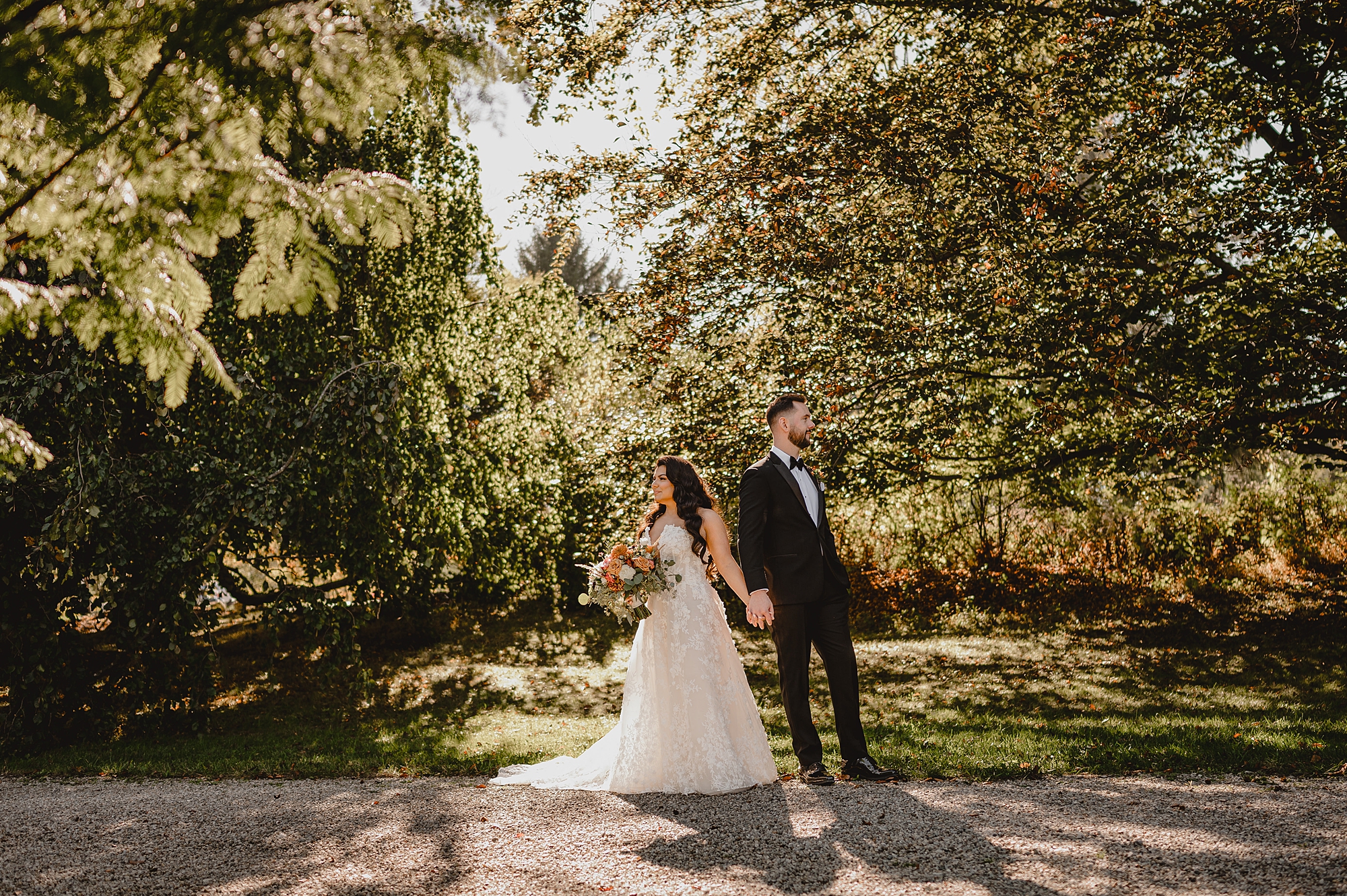 newlyweds hold hands standing back to back in garden at Crossed Keys Estate