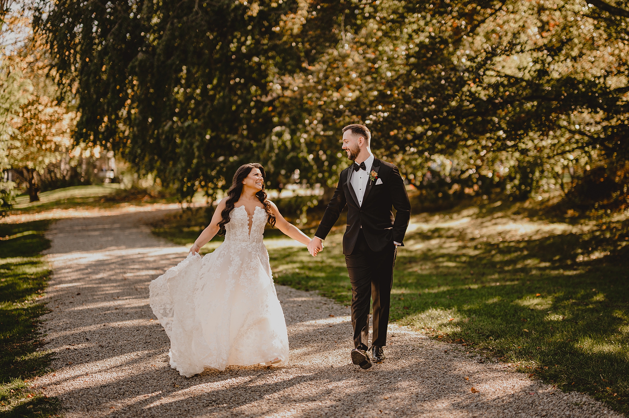 newlyweds hold hands walking down pathway at Crossed Keys Estate