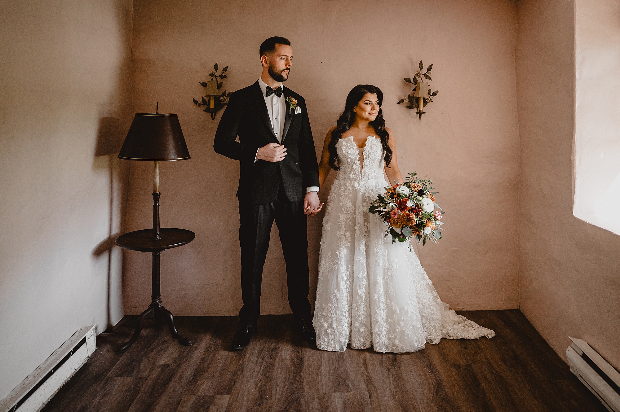 bride and groom hold hands standing between dried flowers at Crossed Keys Estate