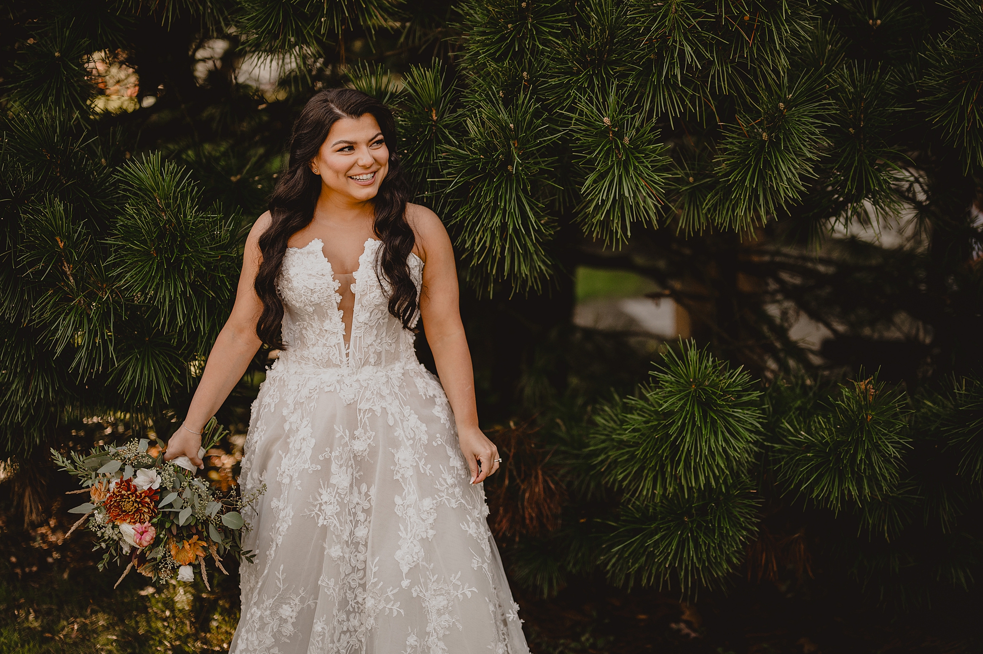 bride laughs in front of wall of greenery at Crossed Keys Estate