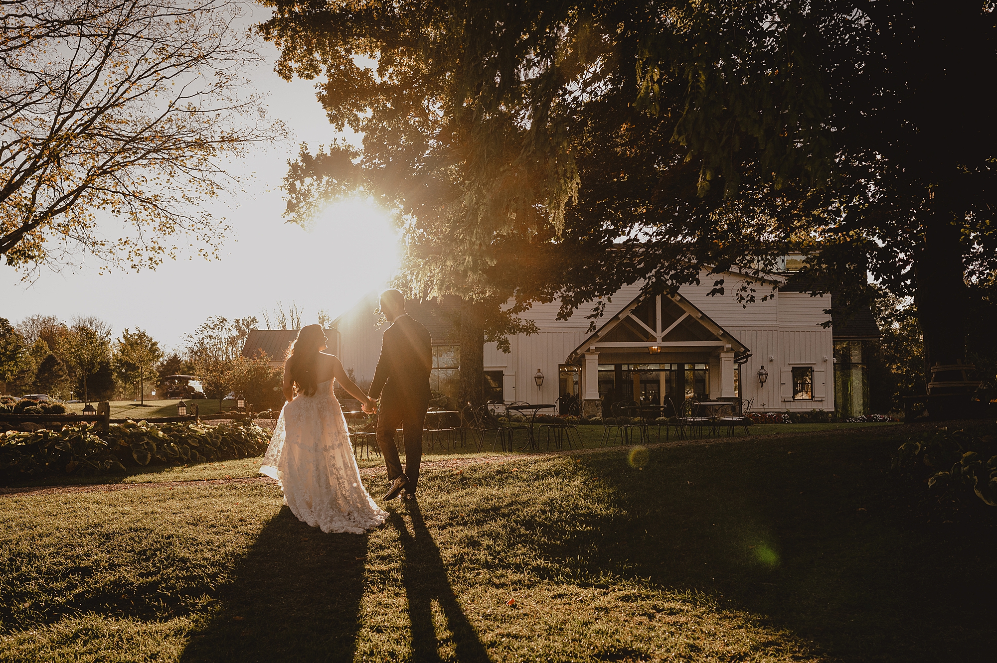 newlyweds walk towards oak tree at sunset at Crossed Keys Estate