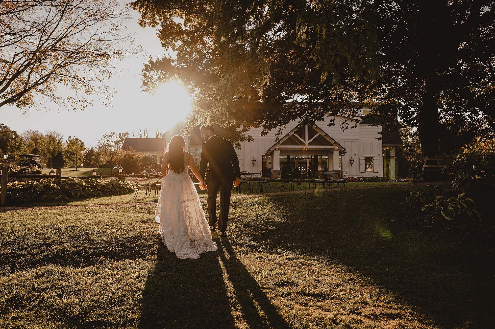 newlyweds walk towards oak tree at sunset at Crossed Keys Estate