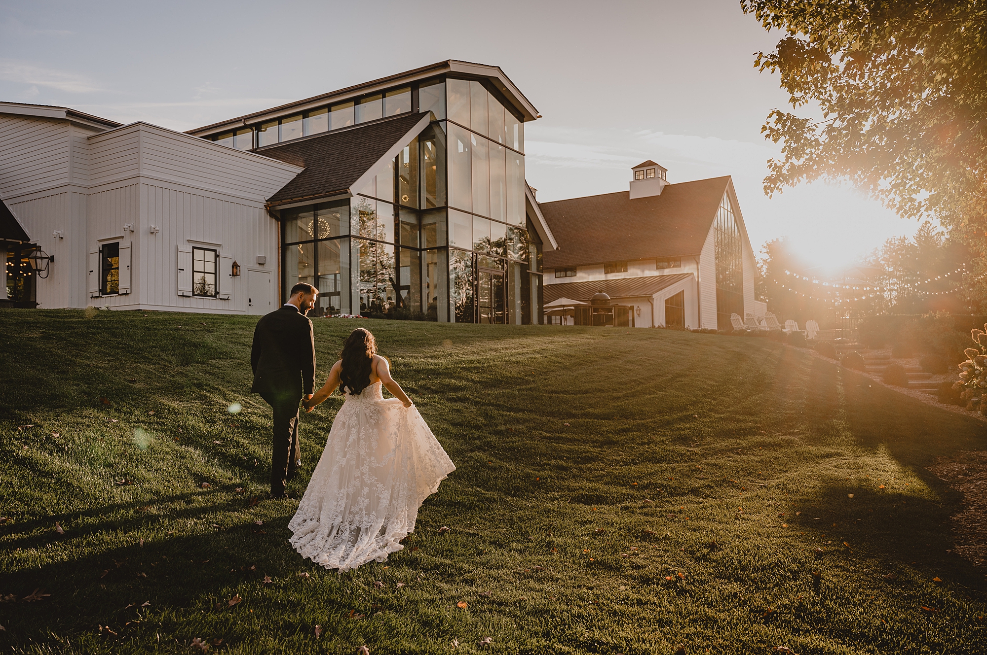 bride and groom walk uphill towards window wall at Crossed Keys Estate