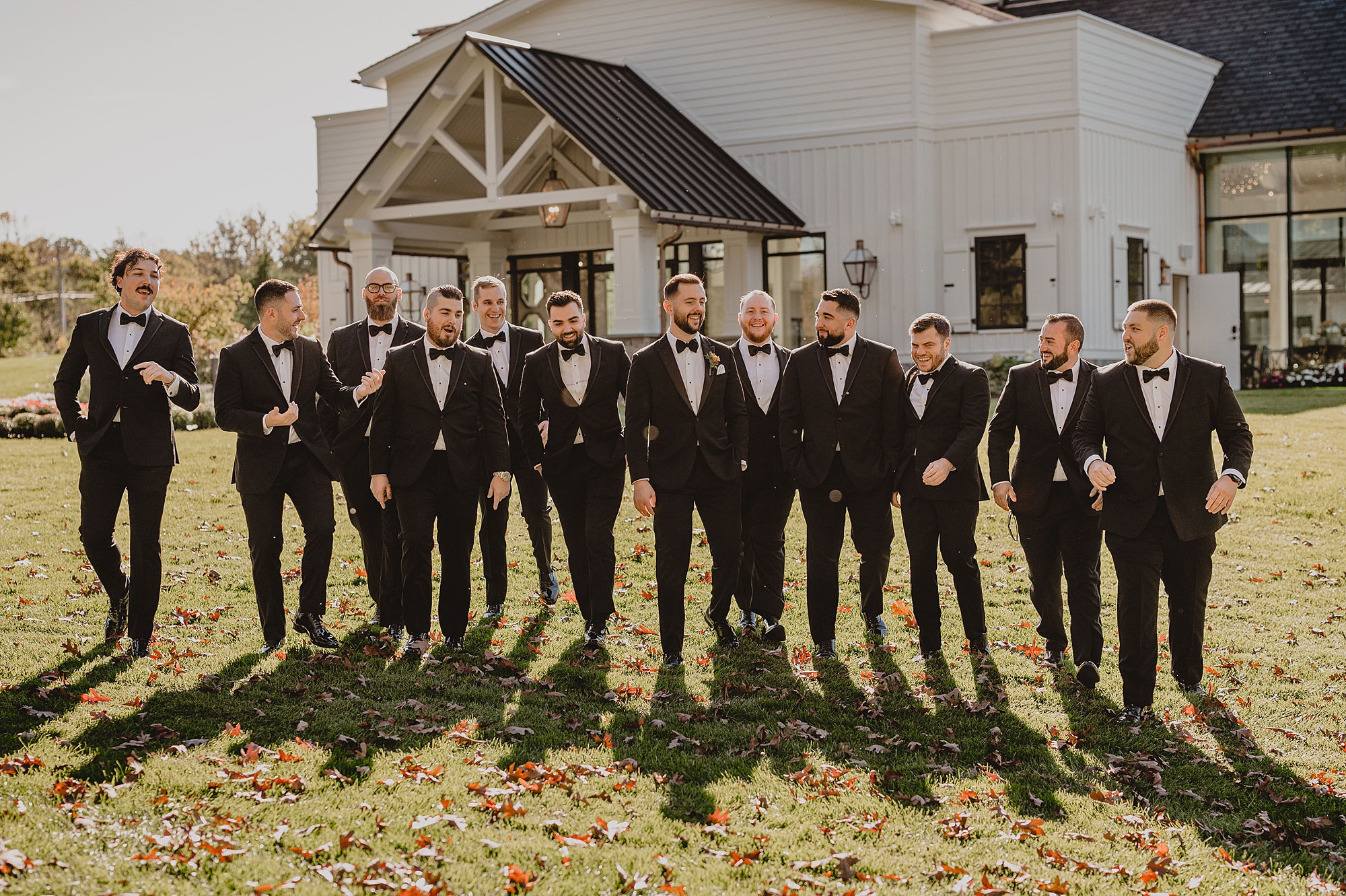 groom walks with groomsmen in black suits down hill at Crossed Keys Estate