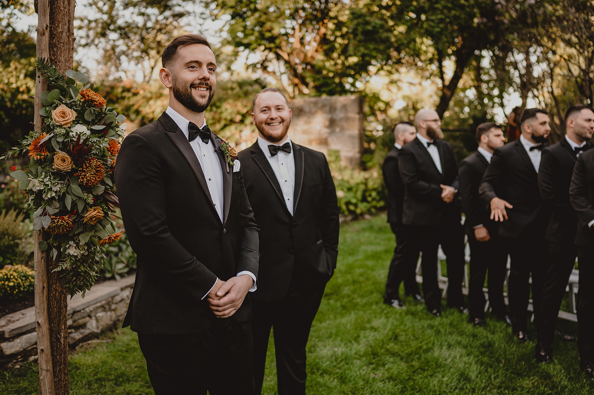 groom laughs with groomsmen before outside wedding ceremony at Crossed Keys Estate