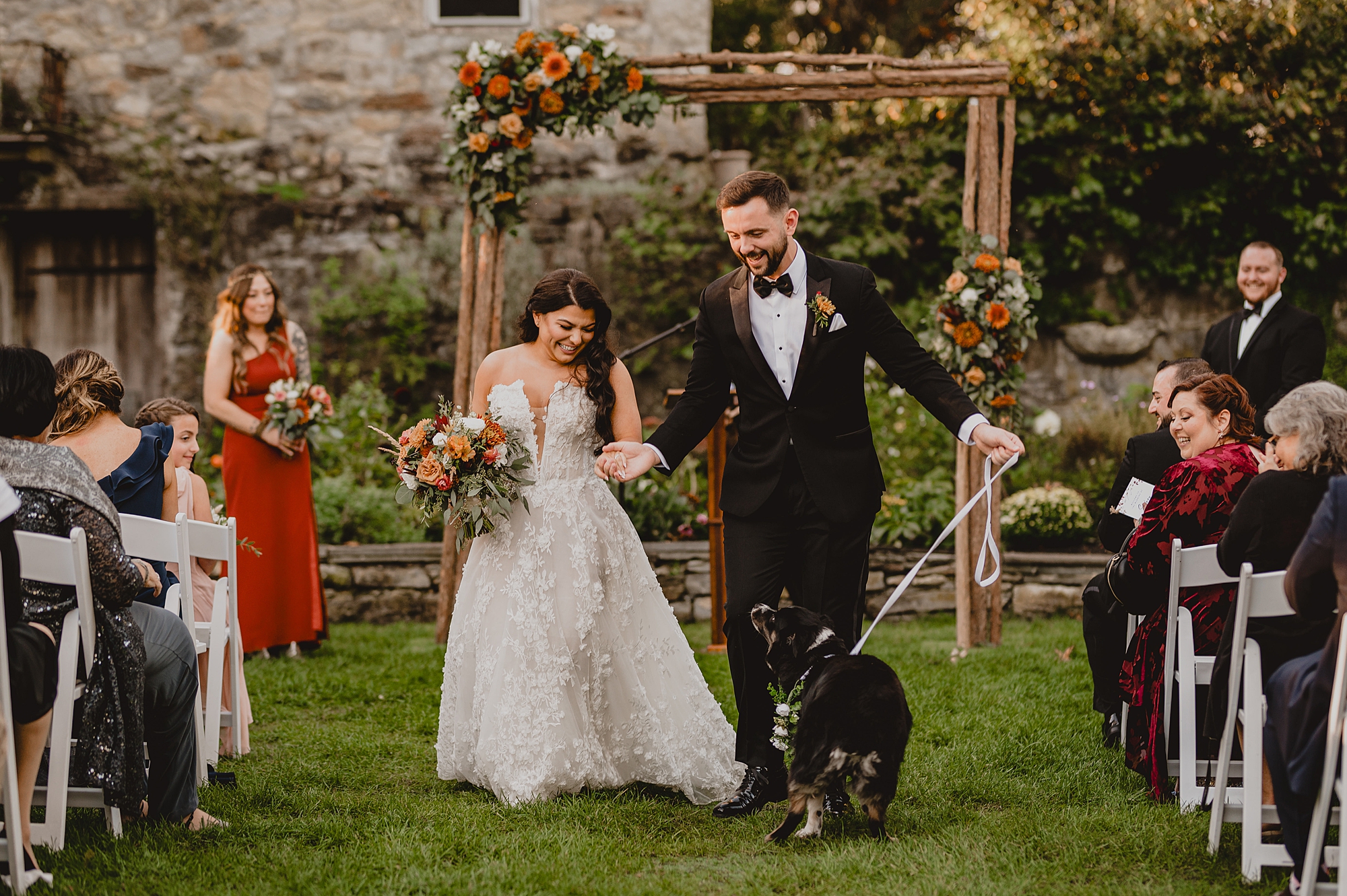 bride and groom walk with dog up aisle after ceremony at Crossed Keys Estate