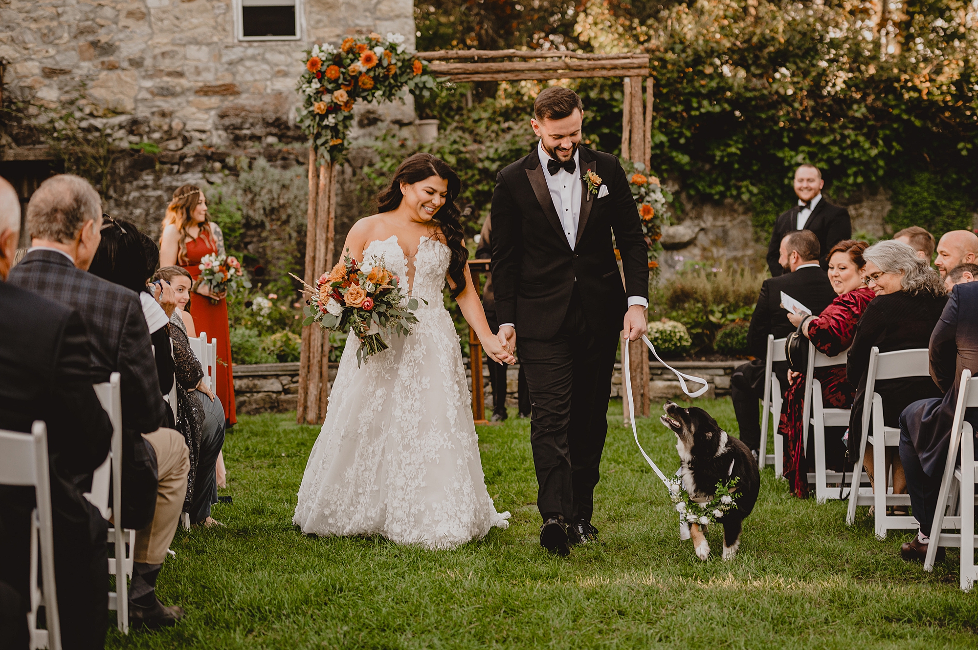 newlyweds walk up aisle with dog on leash