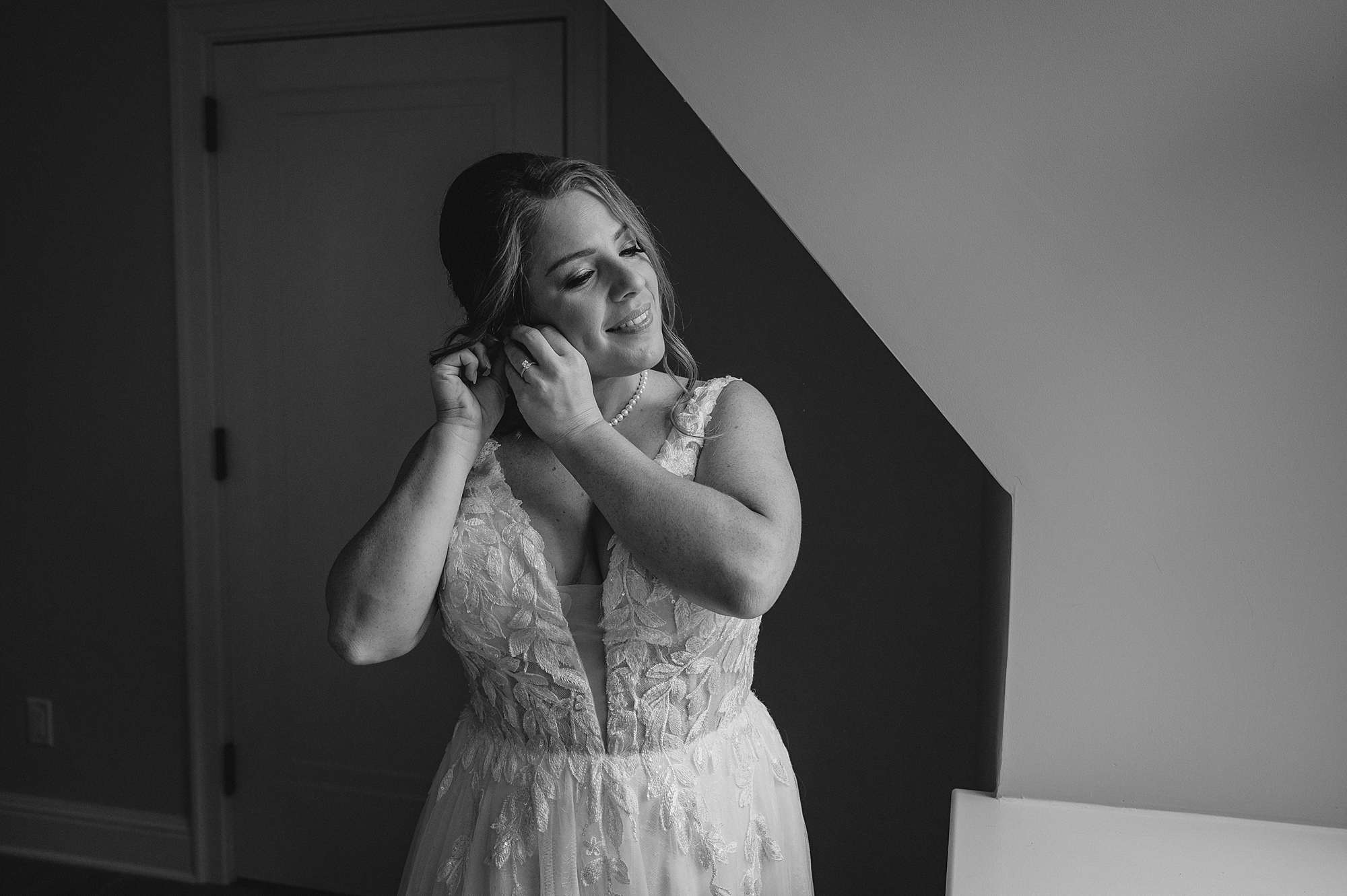 bride leans head to adjust pearl earring