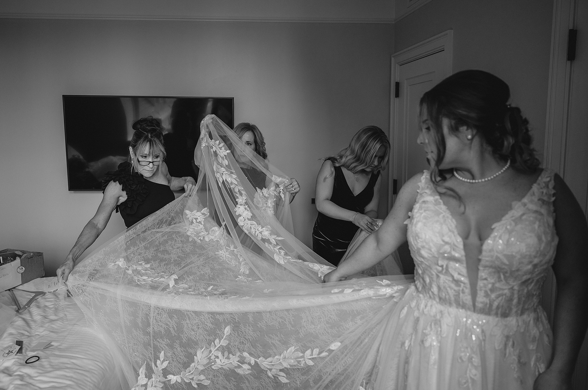 bridesmaids help bride fluff lace top of gown