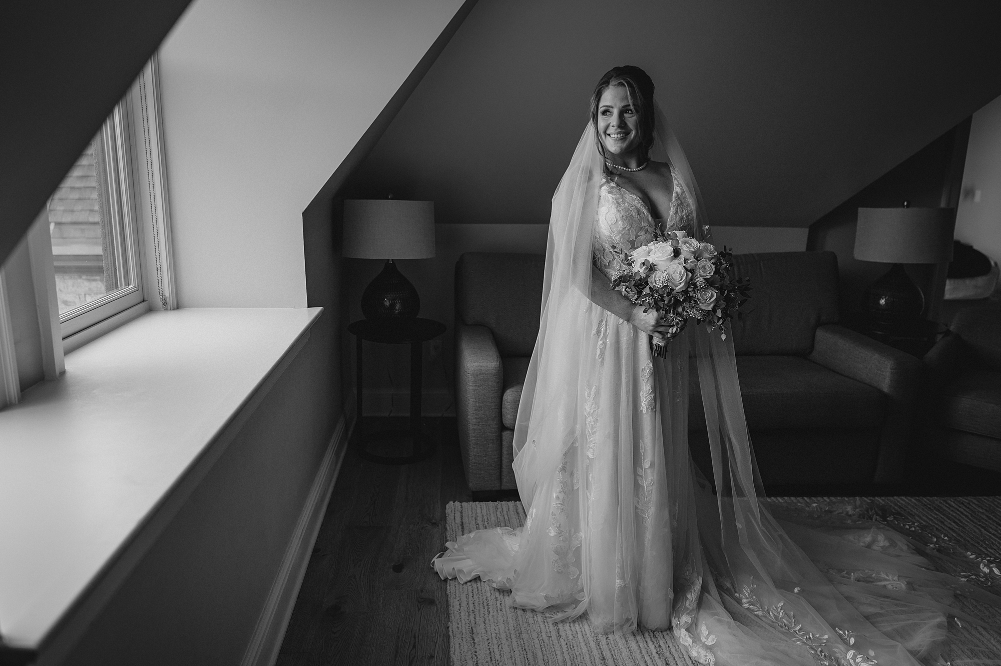 bride stands with veil around her shoulders holding bouquet of flowers 