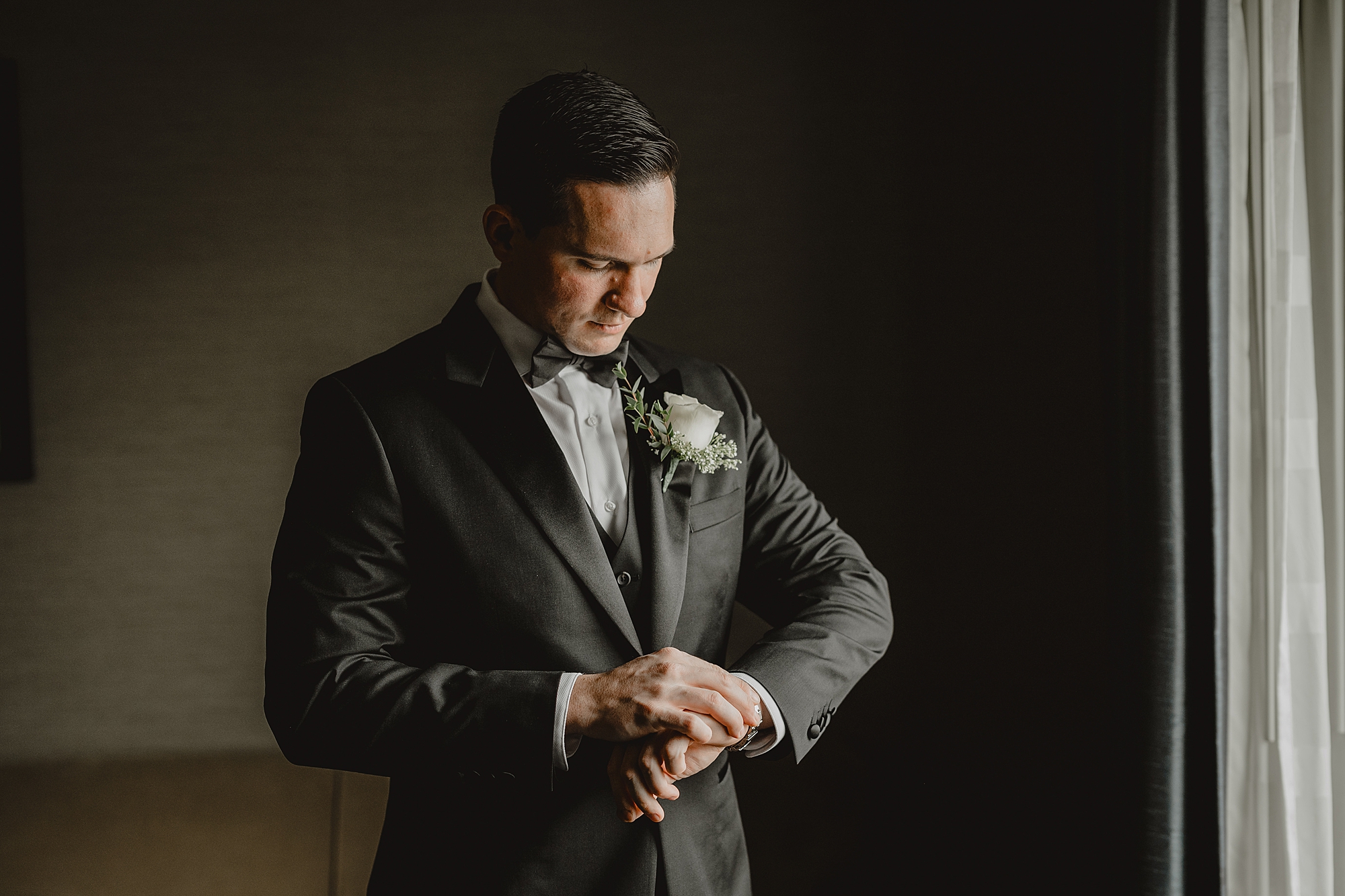 groom adjusts watch and cufflinks while preparing for wedding